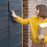 Woman getting parcel from cell of automatic post terminal outdoors