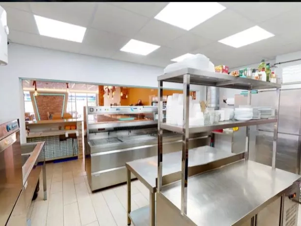 Shows a well-equipped stainless steel kitchen and food preparation areas