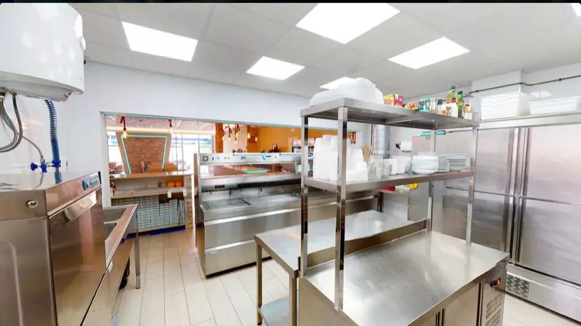 Shows a well-equipped stainless steel kitchen and food preparation areas